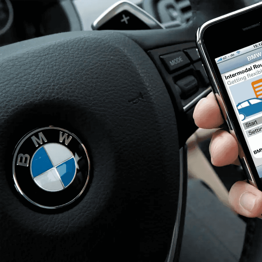 Close up of BMW steering wheel with person holding a smartphone