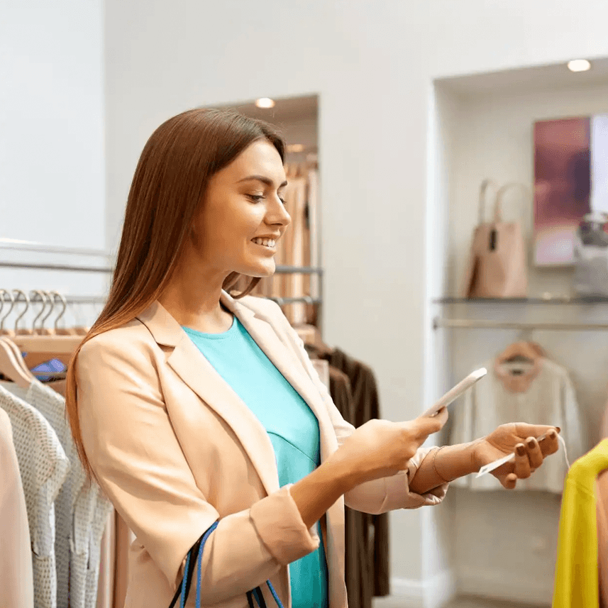 Young woman scanning price tags with her smartphone in a clothing store